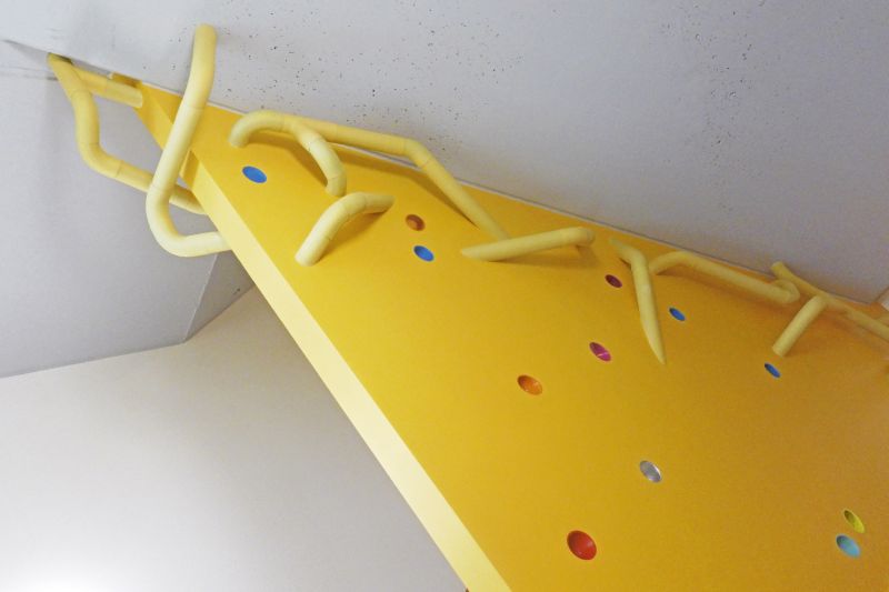 gelbe Treppenwand mit gelben Rohren als Mäusegänge